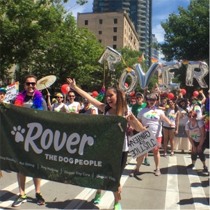 Rover teammates having fun in a diversity parade. Everyone is wearing a diversity T-shirt and a group of employees are holding silver balloons that spell Rover.