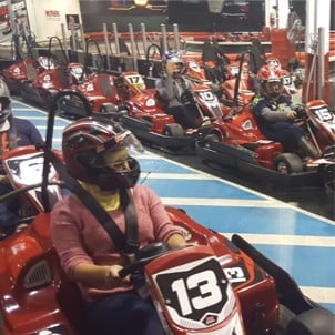 Rover teammates wearing helmets buckled into go karts waiting to start a race