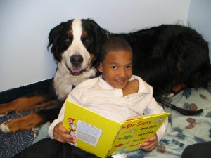 Boy reads book to dog - service dogs teaching kids to read