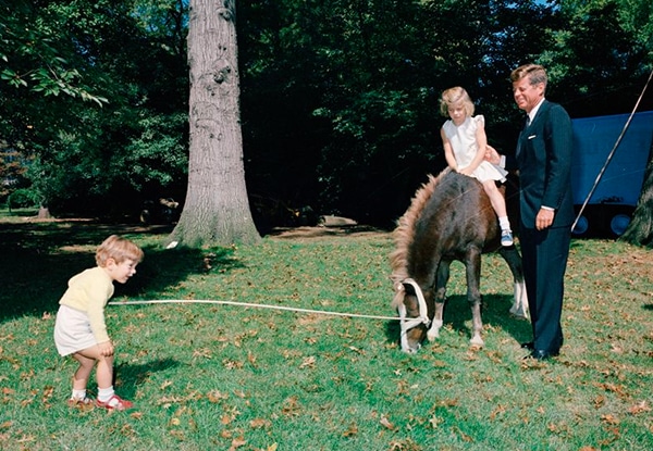 JFK with Caroline riding Leprechaun the horse and JFK Jr. off to the side