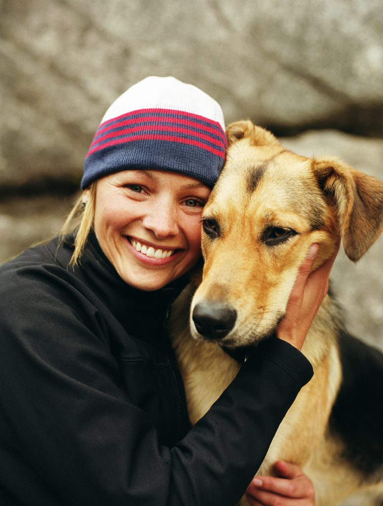 Woman wearing knit cap, hugging dog, portrait