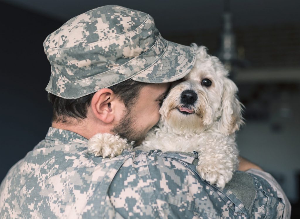 A soldier hugs his service dog.