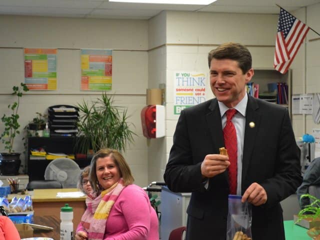 Legislative Assemblyman Billy Jones tries an Eagle Treat on a school visit