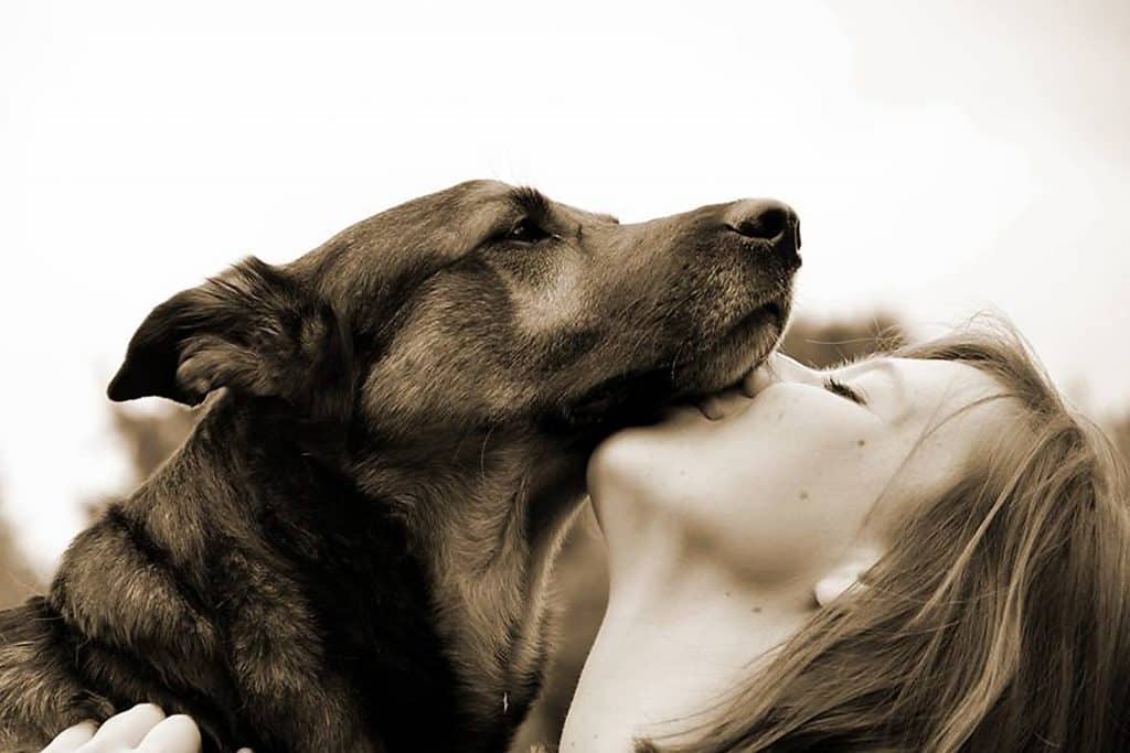 en dam kysser sin hund under hakan