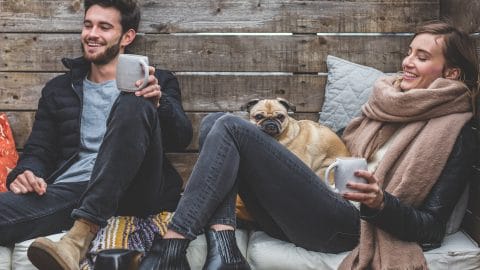 Two people drinking coffee cuddling with Pug