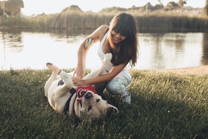 jeune femme qui joue avec son chien au parc