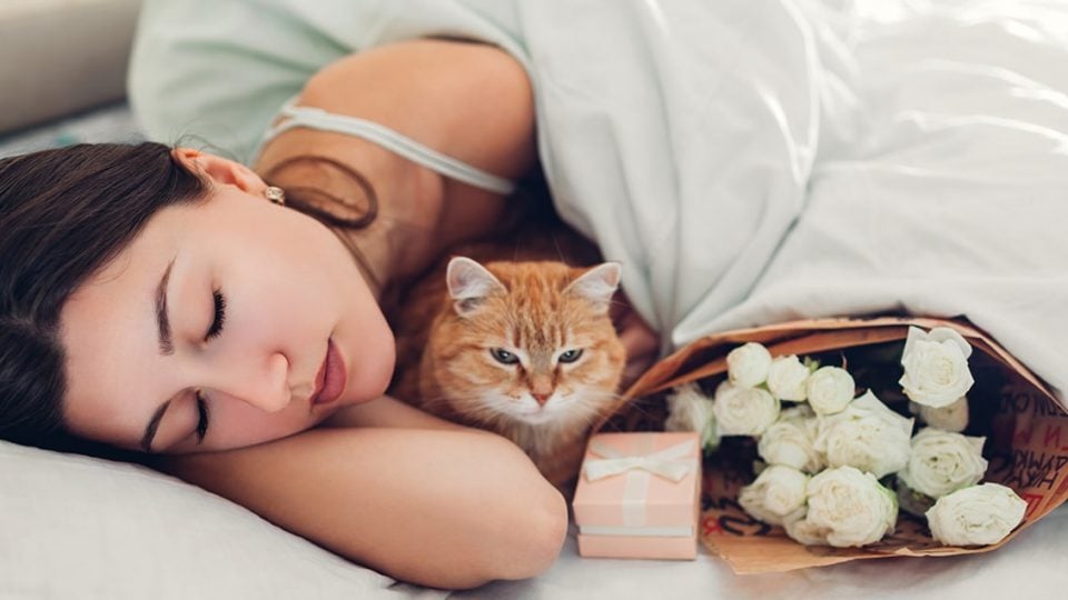 woman in bed with cat and gifts