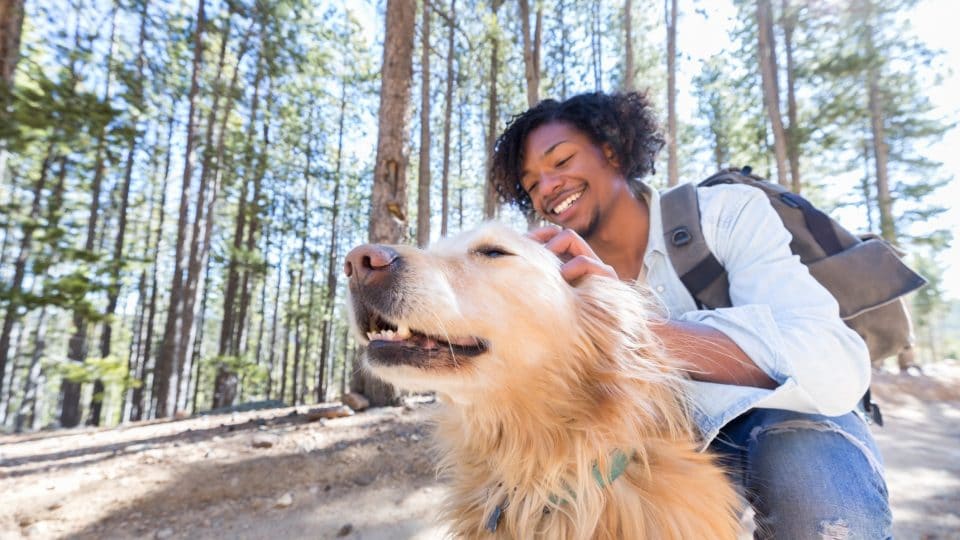 Young man stops on walking trail to praise dog