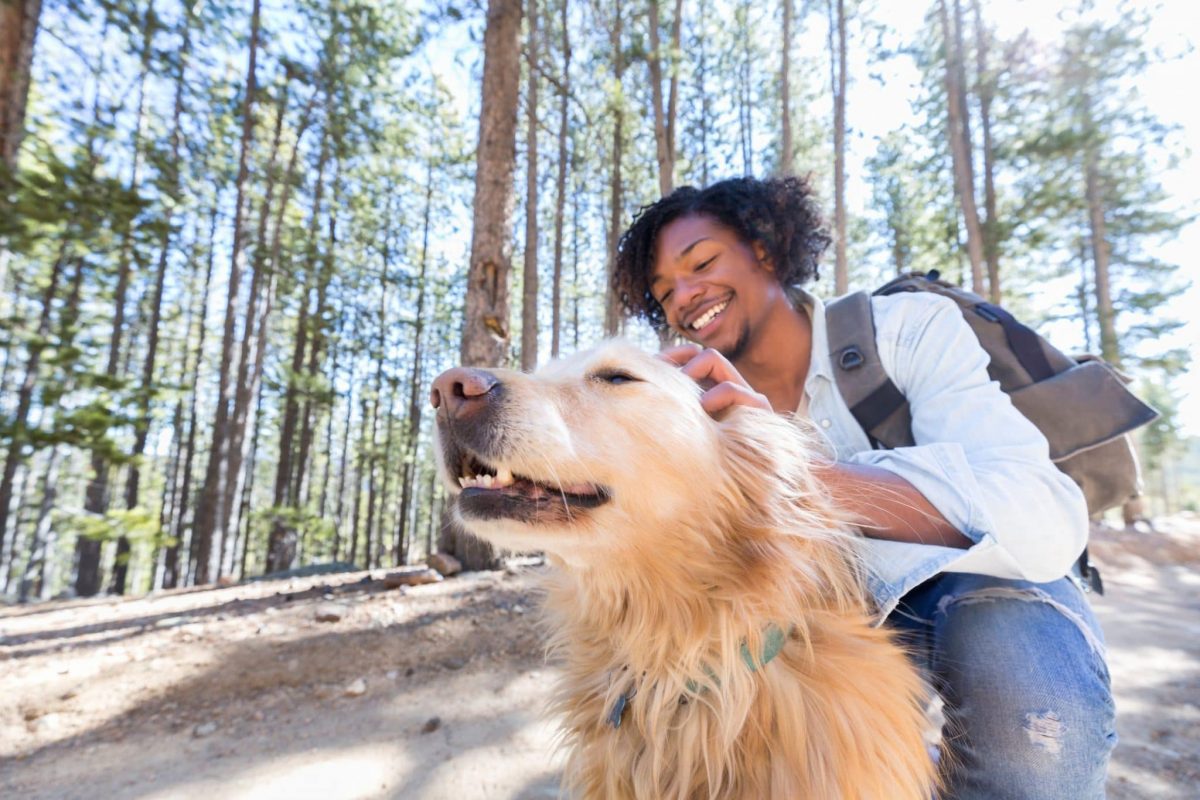Young man stops on walking trail to praise dog