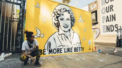 Artist Corie Mattie poses by her Betty White Mural