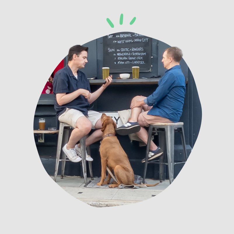 Two friends at a pub with a dog by their side