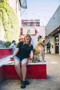 A dog and a human pose on a red bench outside Parson's restaurant