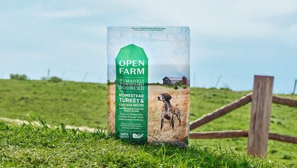bag of Open Farm food in grassy field with blue sky