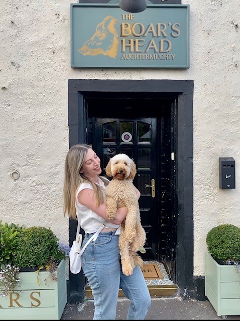 A woman and her dog outside The Boar's Head pub in Scotland