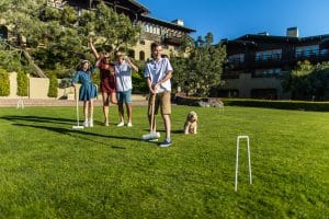 A family and their dog play croquet