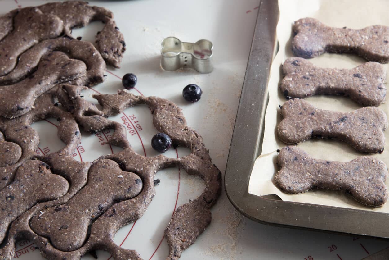 Bone-shaped blueberry dog biscuits on baking sheet