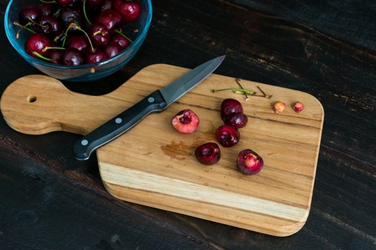 Pitting cherries on cutting board