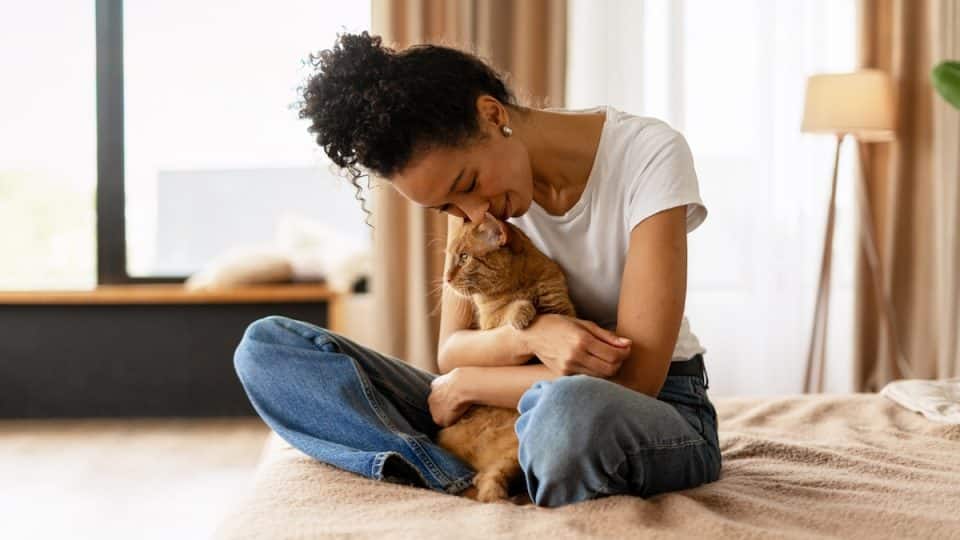 Woman snuggling cat on bed