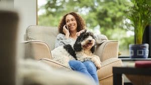 Woman talking on the phone with dog in her lap