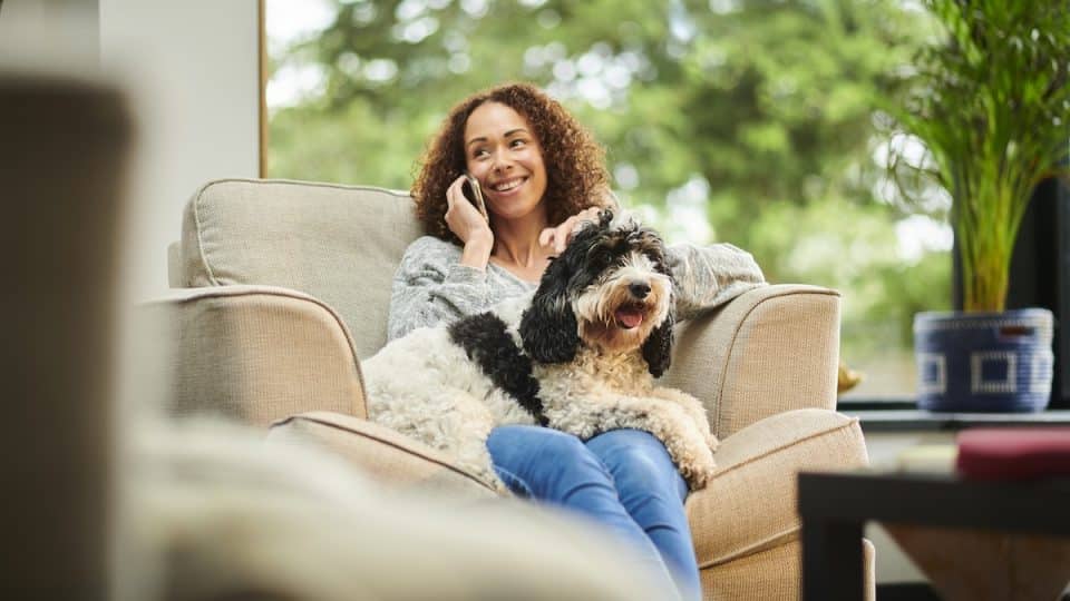 Woman talking on the phone with dog in her lap