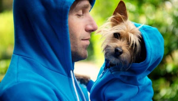 Person in blue hoodie holds dog wearing blue hoodie