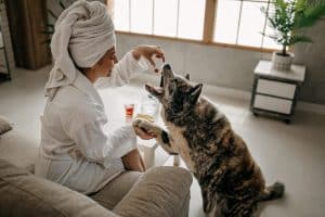 Woman refreshed after shower, feeding her dog treats in a hotel room