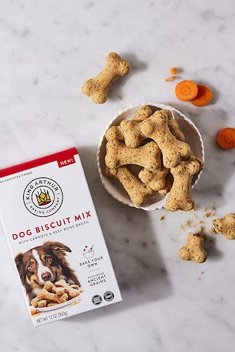 A box of dog biscuit mix next to a bowl of baked treats.