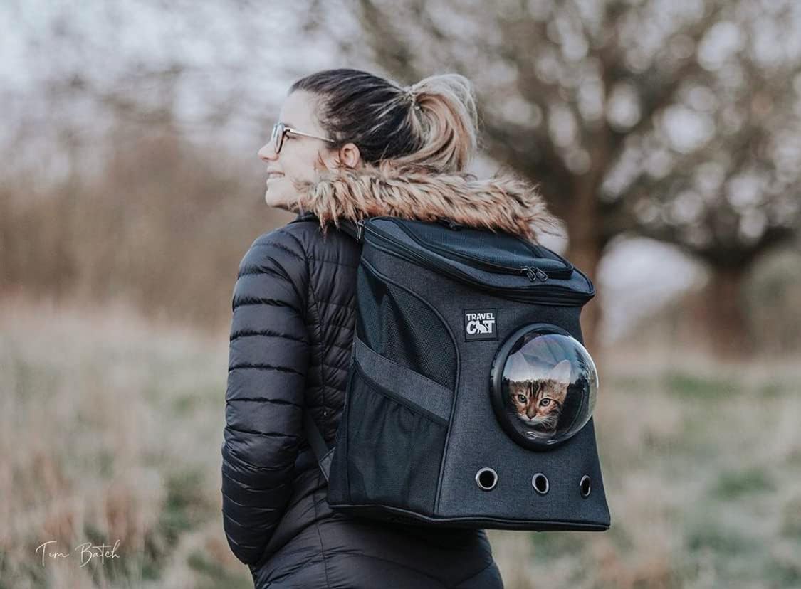 woman in black coat carrying a cat in a backpack