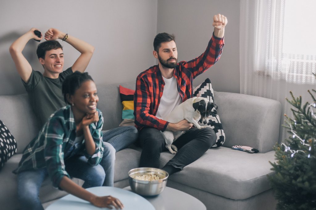 Group of friends spending time together watching TV at home