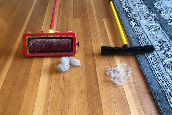 Two carpet rakes with piles of pet hair next to them