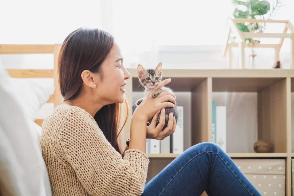 A woman happily holding her new kitten