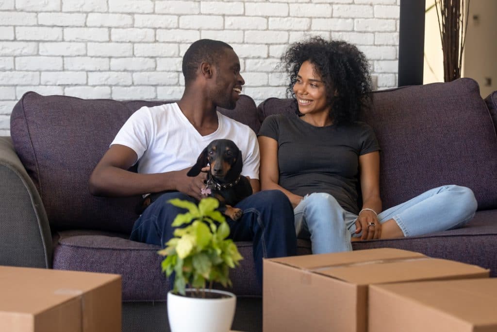 Young Black couple relaxes on couch with dog after a day of moving
