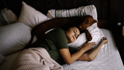 girl and her dog best friend asleep on a bed together