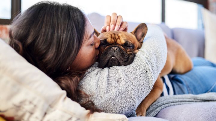 Woman and dog cuddle on couch