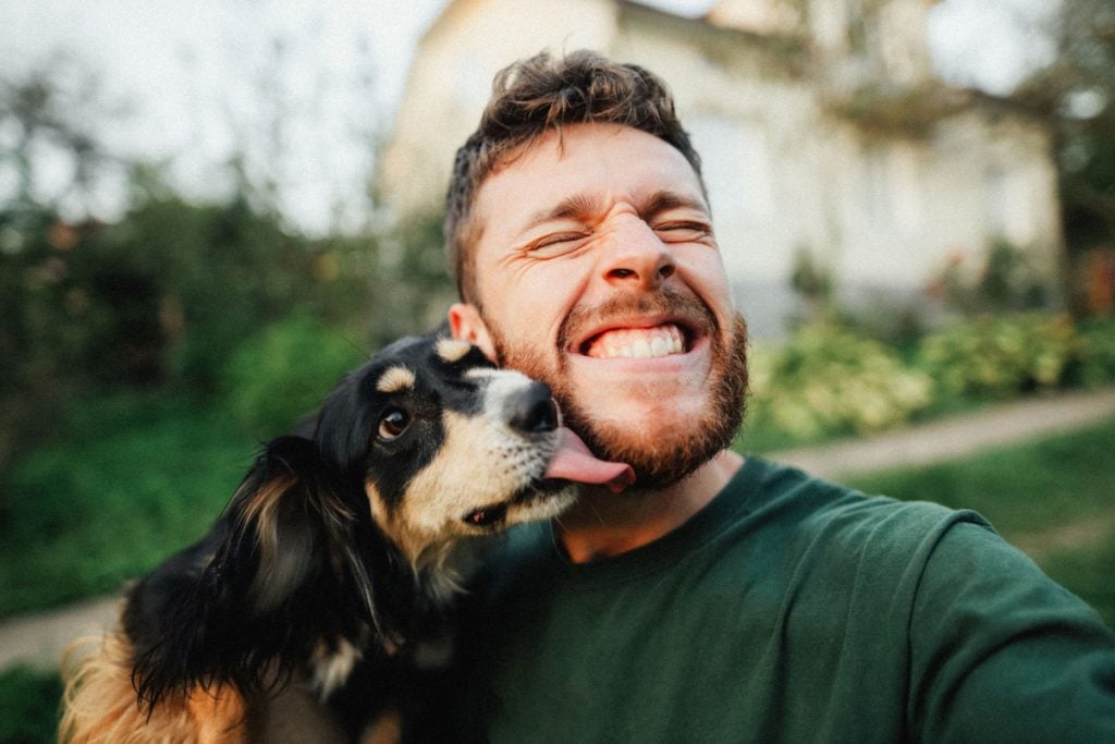 Man plays with dog, who licks his chin