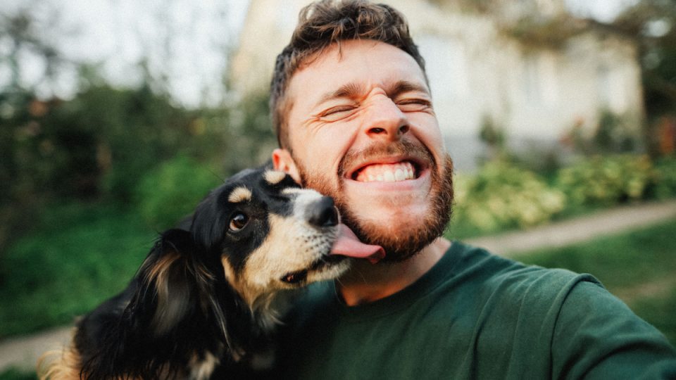 Man plays with dog, who licks his chin
