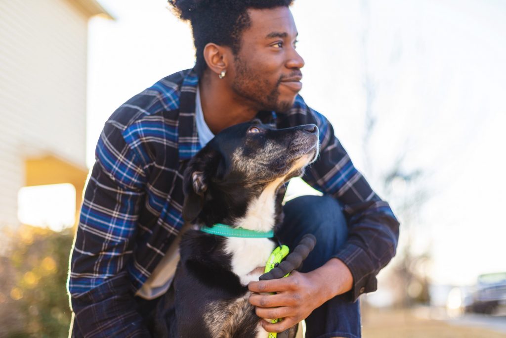 A Black man cuddling with his dog