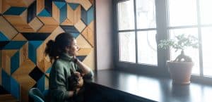 Beautiful woman with pet dog sitting in cafe waiting for coffee, looking at window and smiling.