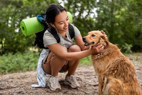 Une femme en randonnée dans une forêt avec son chien