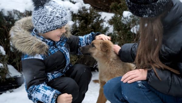 Woman introducing child to puppy in the snow