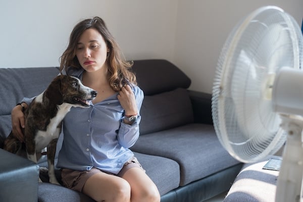 Young woman in front of cooling fan with her dog 
