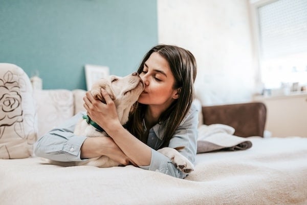 Woman hugging dog on bed
