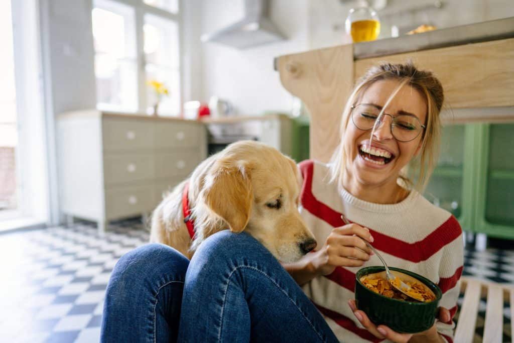 Foto de una joven y su perro en una cocina por la mañana