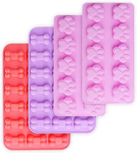 Four pink and purple silicone mold trays for baking dog treats or freezing them