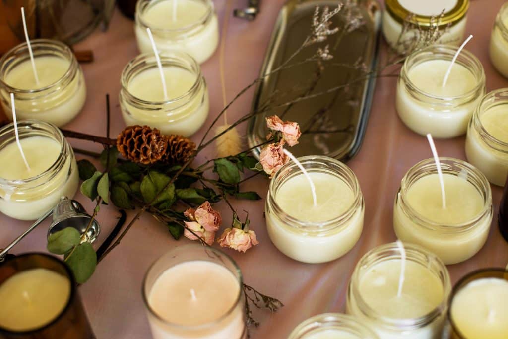 Soy Candles poured into recycled bottles and jars. Many soy wax candles together on store or workshop background. . Ecological and vegan business.