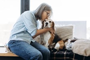 Person sitting on couch kissing dog's head