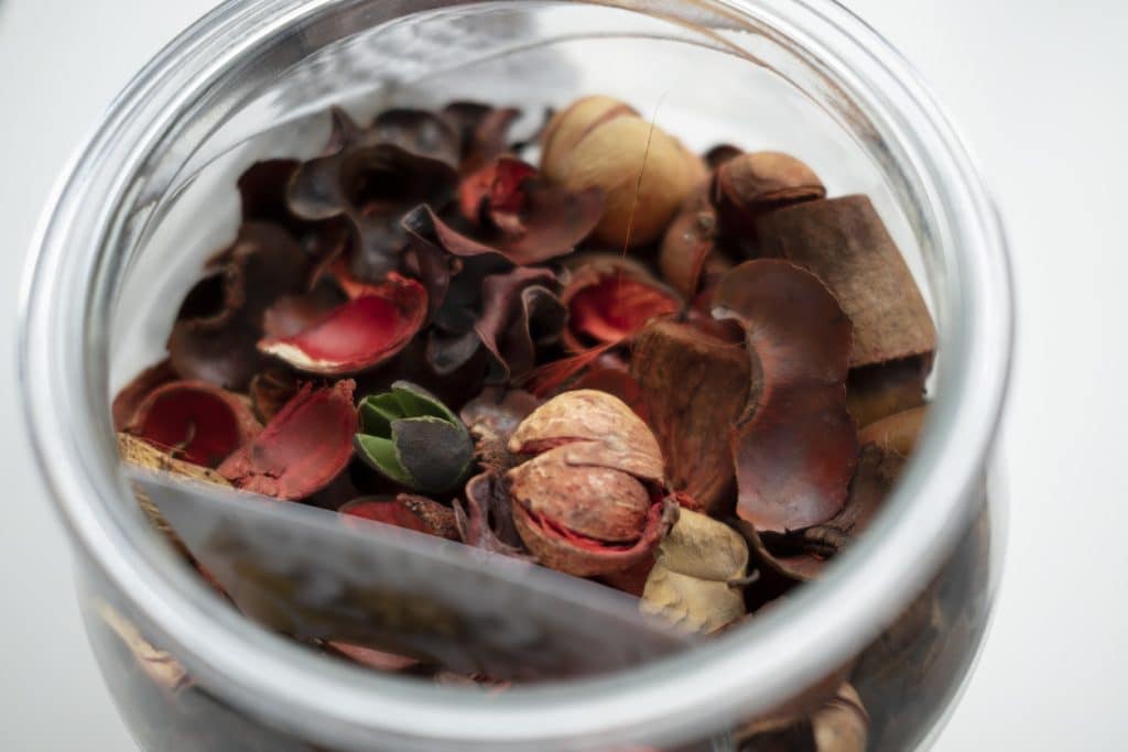 Close up view of potpourri or dried petals flowers in glass jar used for aromatherapy.