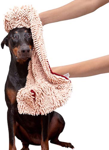 A brown and black dog getting dried off with a dog towel. 