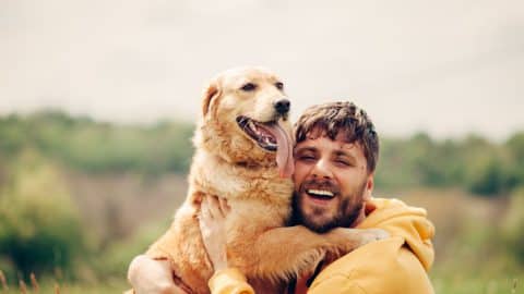 Man hugging dog and smiling