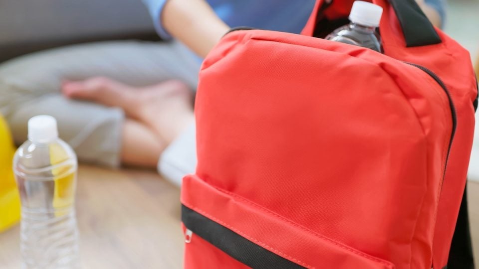 Person packing up red emergency backpack